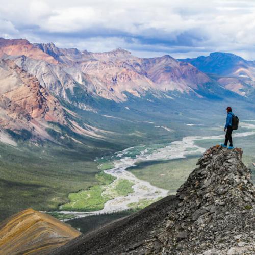 Hiker standing on peak, overlooking valley.